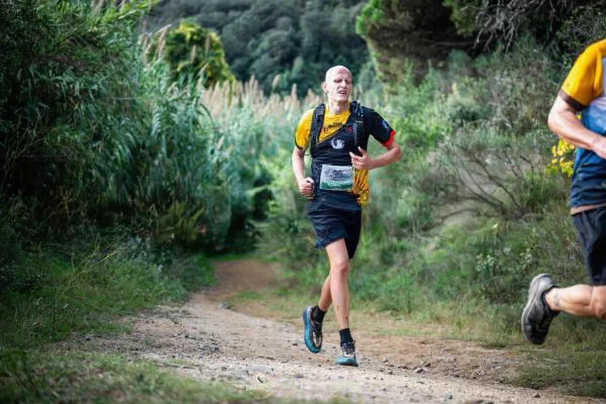 Corredor de trail running subiendo una cuesta empinada durante una carrera de montaña.